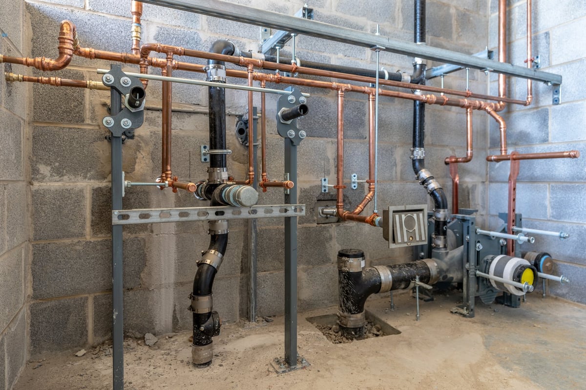 Plumbing rough in for a new commercial bathroom with a block wall