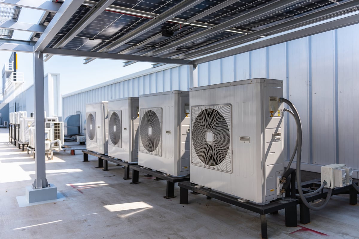 Row of Industrial Air Conditioner Condenser Units on Factory Rooftop with Solar Panel Canopy