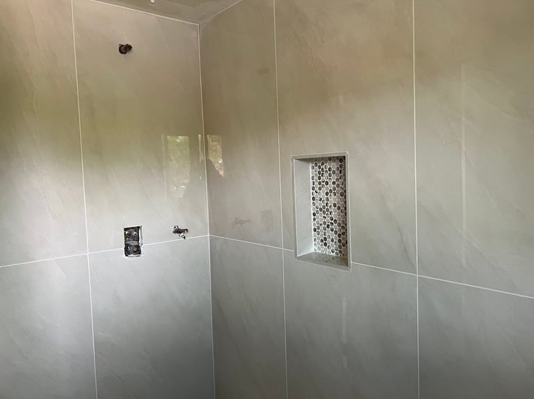 Modern shower enclosure with glass walls and built-in niche with mosaic tile insert