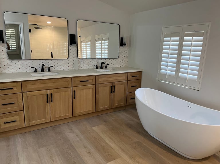 Modern bathroom with dual vanity, two mirrors, white freestanding tub, and white shutters