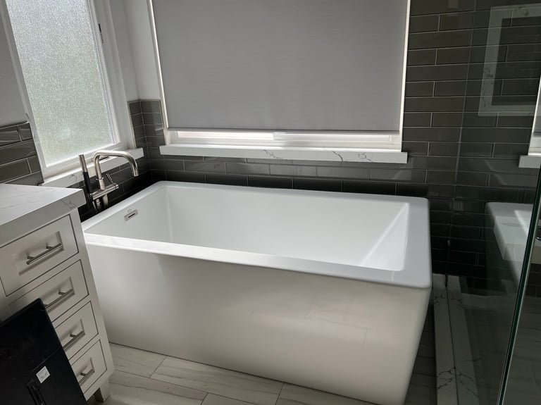 Modern bathroom with white rectangular soaking tub, dark green tile walls, natural light from window