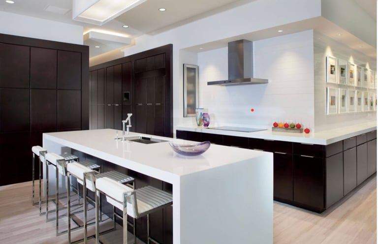 Modern kitchen with white island, black cabinetry, stainless steel range hood, and bar seating