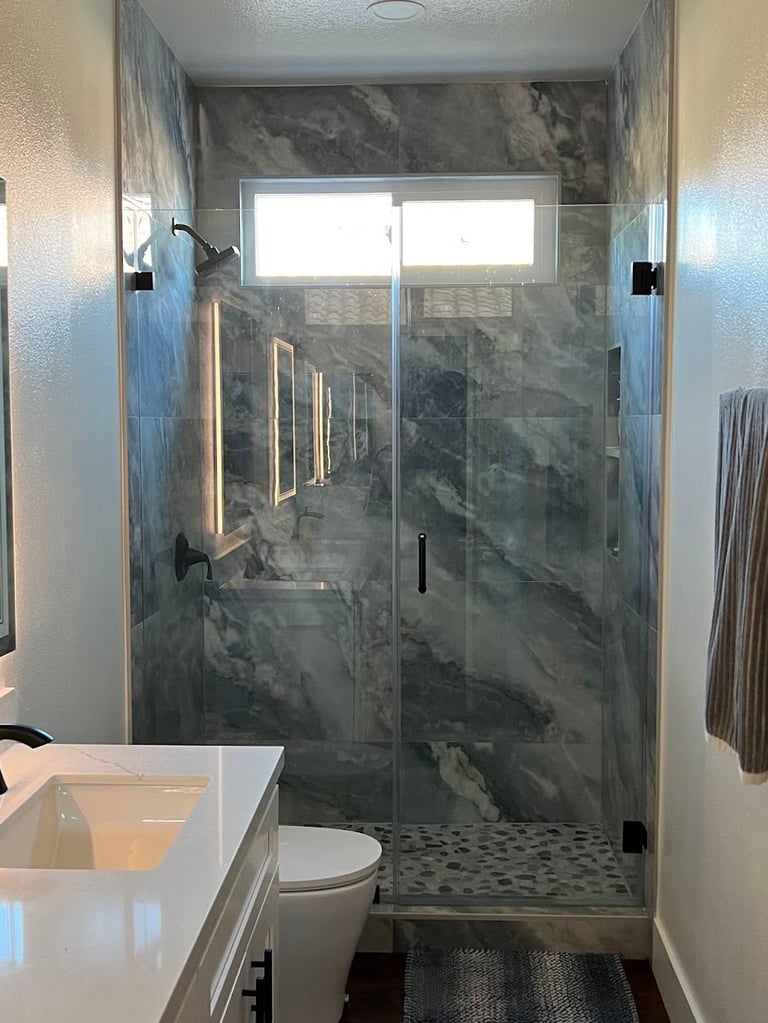 Modern bathroom with glass shower enclosure, marble tile walls, white vanity sink