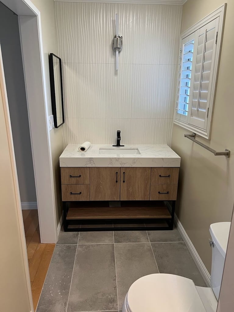 Modern bathroom with wood vanity, white countertop, framed mirror, subway tile backsplash, and slate flooring