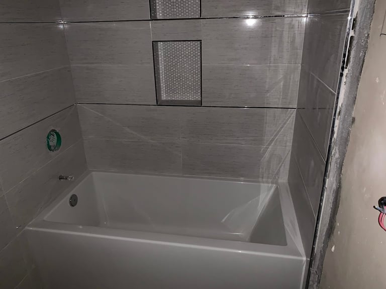 Modern bathroom shower with gray tile walls, built-in shower bench, and integrated wall niches