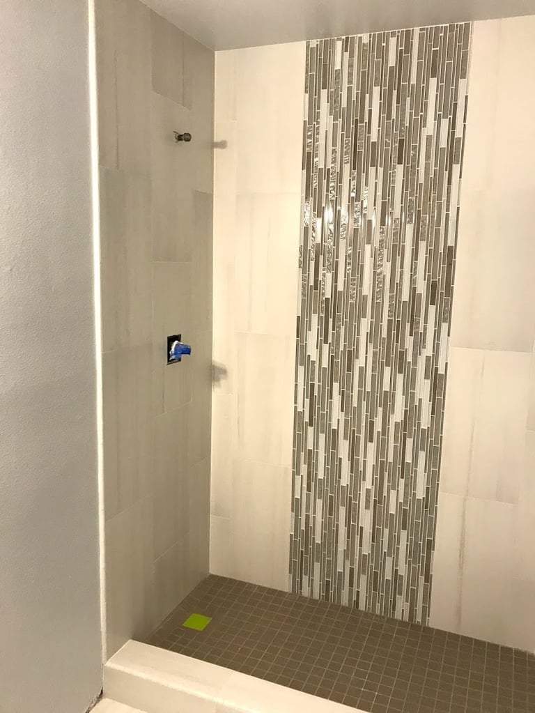 Modern shower enclosure with vertical stripe tile accent wall and dark floor tiles