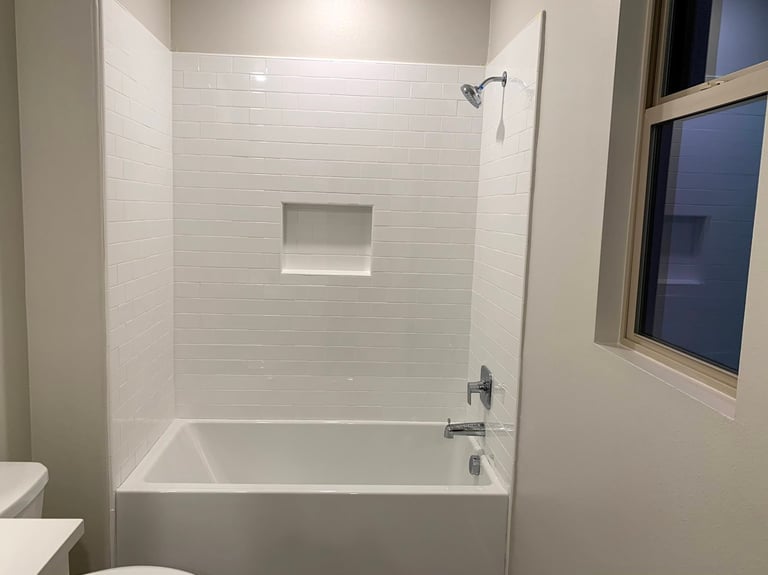 Modern bathroom with white subway tile shower-tub combo, glass door, and built-in niche