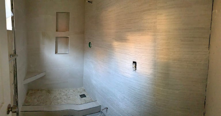 Modern bathroom shower enclosure with glass doors, subway tile walls, and stone flooring
