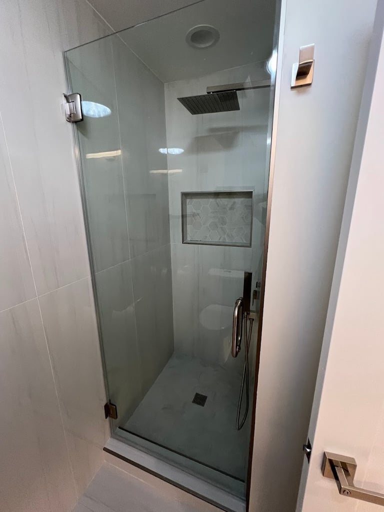 Modern glass shower enclosure with rainfall showerhead and built-in niche in a tiled bathroom
